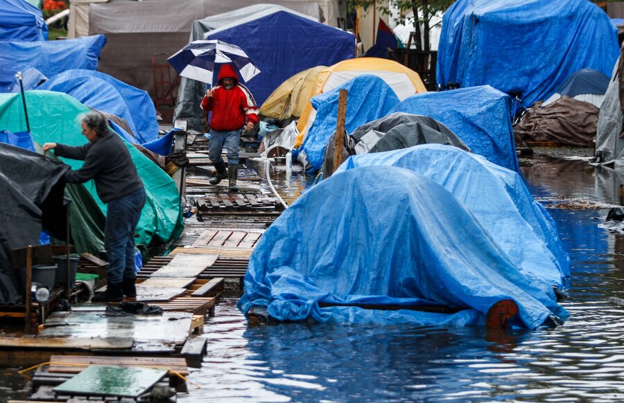 Nickelsville's resident and head of security Steve Westfall walks thru the flooded camp last November. (Photo: Nick Adams)